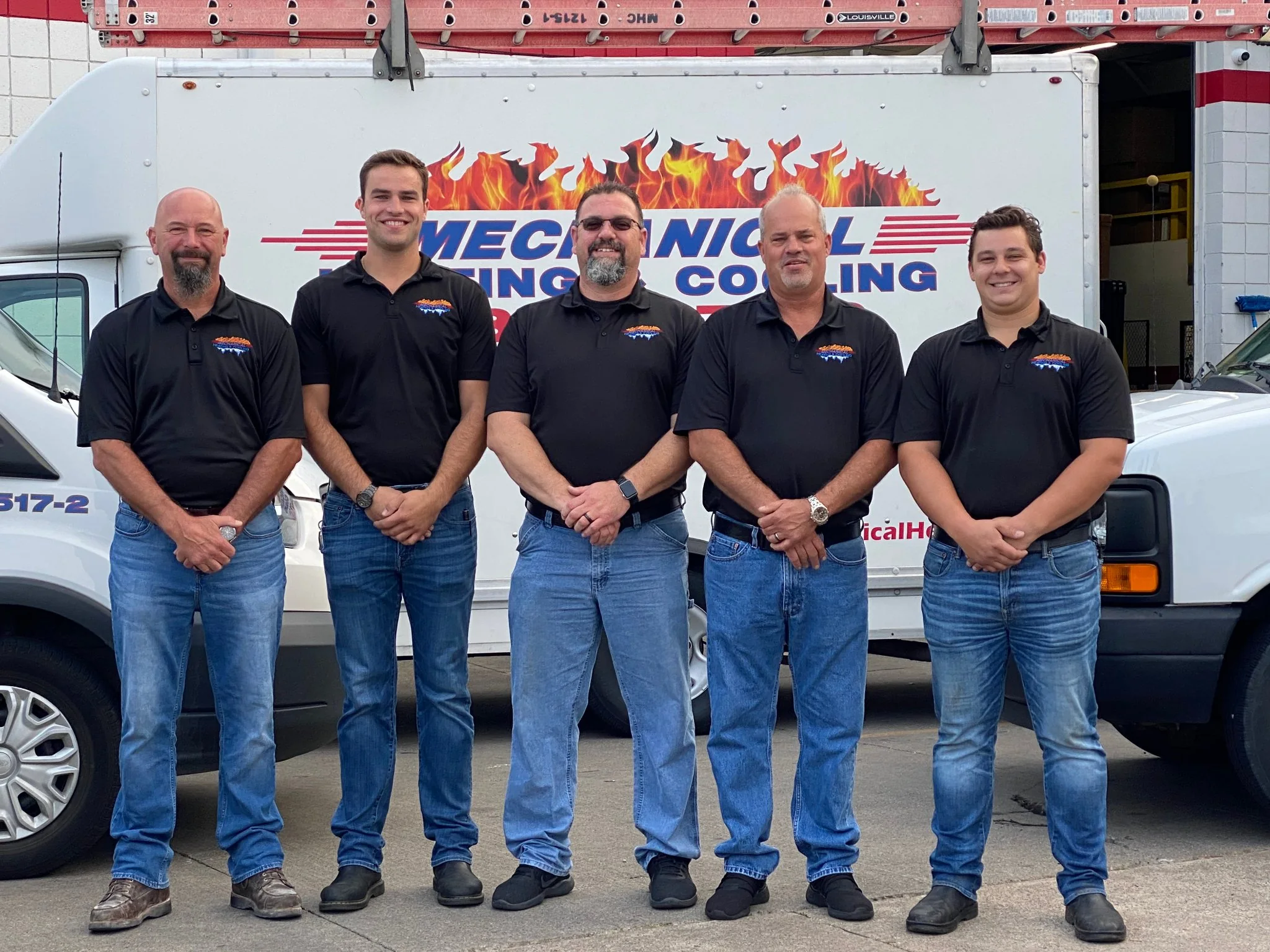 Mechanical Heating, Cooling & Electrical team members standing in front of a branded service truck