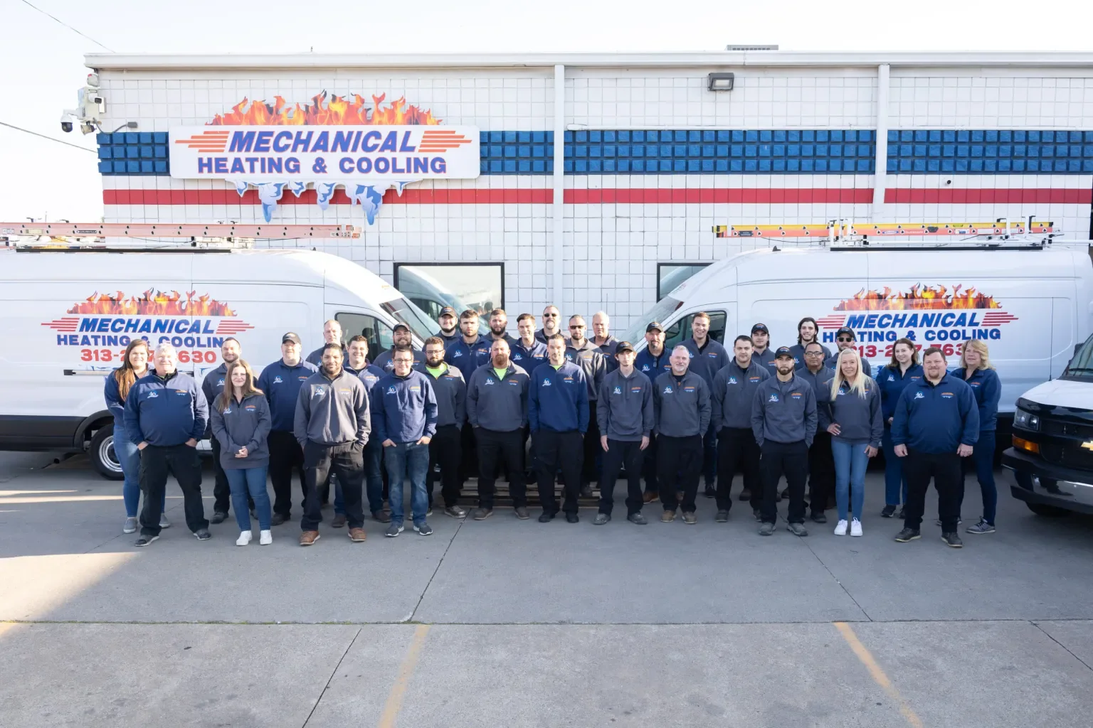 Mechanical Heating, Cooling & Electrical full team posed between company service vans